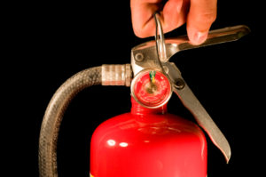pulling pin on red fire extinguisher