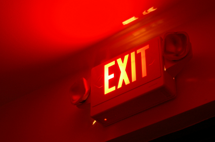 Lit emergency exit sign above a doorway in a commercial building.