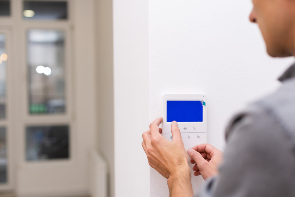 Man installing security alarm system on light wall at home, closeup